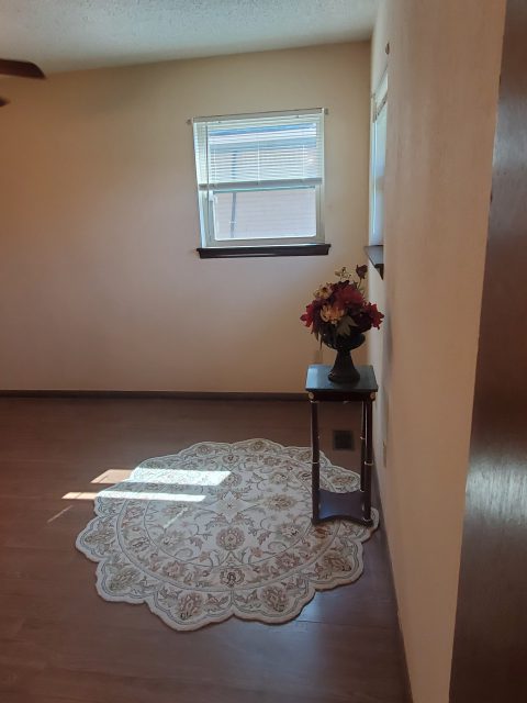 A bedroom with a window and flower stand