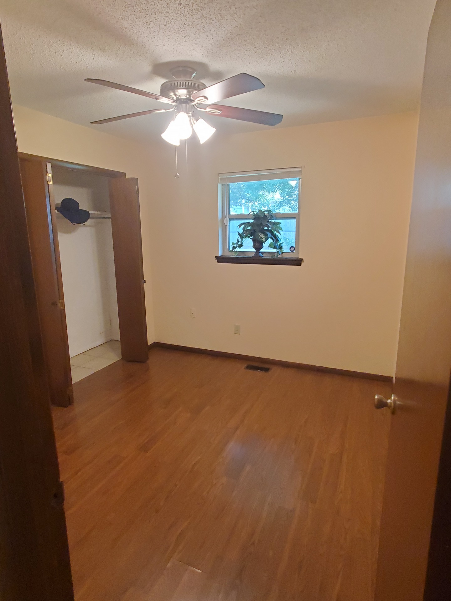 A bedroom with closet, window and ceiling fan