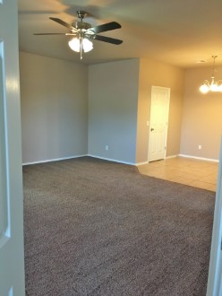 A large room with ceiling fan and carpet flooring.