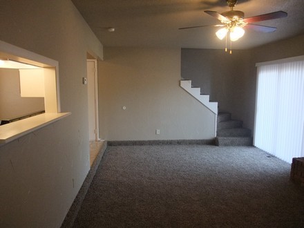 A room with carpet and ceiling fan and stairs